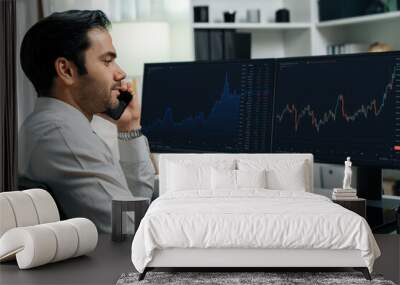 Trader businessman calling to consultant or partner with two stock exchange investment, compare data analysis to invest high profit value dynamic financial technology stock market at office. Surmise. Wall mural