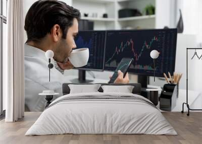 Trader businessman holding coffee cup focusing on dynamic on phone, stock exchange investment screen comparing data analysis to invest high profit financial technology market at home office. Surmise. Wall mural