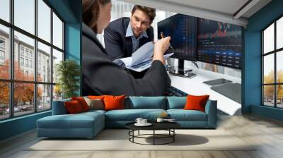 Two business traders discussing value business statistic graph company on paper report analyzing with dynamic stock exchange market currency real time website surround pc screens at office. Postulate. Wall mural