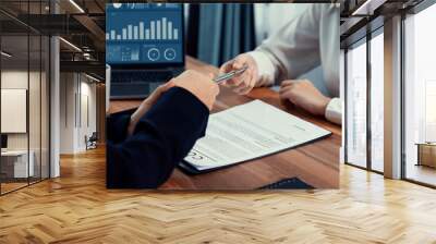 Two businesspeople sit across the desk as business deal is taking place. Corporate attorney handing a pen for client or partner to sign contract paper, sealing the deal with signature. Enthusiastic Wall mural