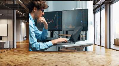 Working young business trader focusing on market stock graph data investment in real time laptop in monitor screens. at modern office. Concept of analyzing dynamic financial exchange rate. Gusher. Wall mural