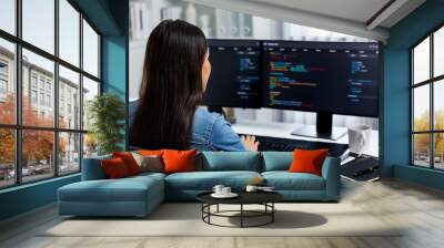 Young Asian in IT developer creating with typing online information on pc with coding program data of website application, wearing jeans shirt. surrounded by safety analysis two screens. Stratagem. Wall mural