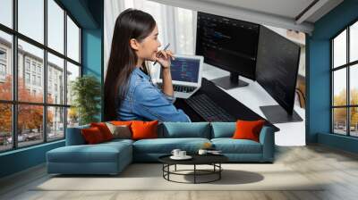 Young Asian IT developer looking online information on pc for beautiful pose with coding program data of website application, wearing jeans shirt. surround by safety analysis two screens. Stratagem. Wall mural