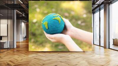 Young boy's hand holding planet Earth globe at natural park background as Earth day to save this planet with ESG principle and environment friendly energy for brighter future. Gyre Wall mural