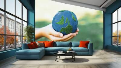 Young boy's hand holding planet Earth globe at natural park background as Earth day to save this planet with ESG principle and environment friendly energy for brighter future. Gyre Wall mural