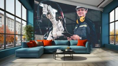 young factory worker working with adept robotic arm in a workshop . industry robot programming softw Wall mural