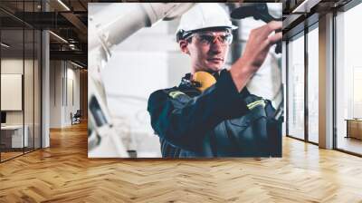 Young factory worker working with adept robotic arm in a workshop . Industry robot programming software for automated manufacturing technology . Wall mural