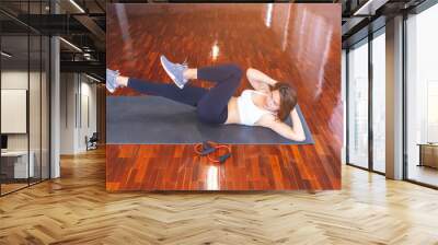 Asian woman workout at home, her sit up. Attractive slim girl in sportswear is doing abs exercises on the floor at home. fitness and gum concept. Wall mural