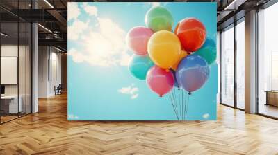 Colorful balloons floating under a bright blue sky, symbolizing celebration and joy. Wall mural