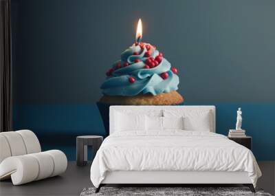 Blue cupcake with red sprinkles and lit candle on a blue background Wall mural