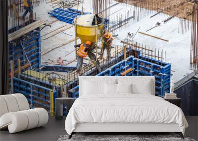 Concreting work at the construction site. Сonstruction workers pour liquid concrete from cement concrete hopper to fromwork installation. Wall mural