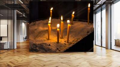 Prayer burning candles in a church on a dark background. Religious concept. Wall mural