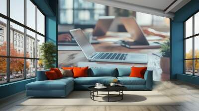 Laptop on a Wooden Table with Blurred Background of People Working Wall mural