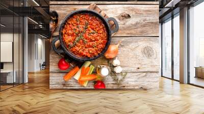 classic italian bolognese sauce stewed in cauldron with ingredients on wooden table, top view, culinary background with space for text Wall mural