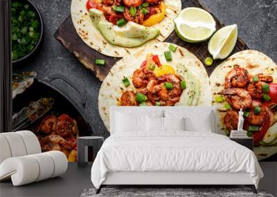 Fajitas in tortillas with fried shrimps, bell peppers and onion served up with avocado and green onions on wooden cutting board, top view, flat lay Wall mural