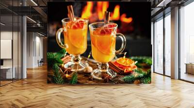 Mulled cider glasses on the background of fireplace fire. Hot mulled spiced apple cider cocktail for winter or autumn time. Wall mural