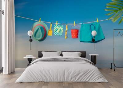 Beach hat, flip-flops and goggles hanging on a clothesline against sea and sky Wall mural