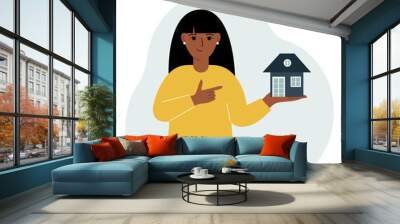 A woman holds a small house in his palm. Concepts of inheritance, real estate transfer, mortgage, credit, loan or house purchase. Wall mural