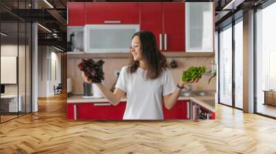 Young happy vegetarian nutritionist woman holds two types of salad in her hands, natural organic food, healthy food at home Wall mural