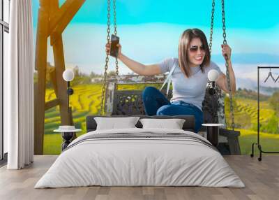 Beautiful girl riding a swing beside a rice field. Wall mural