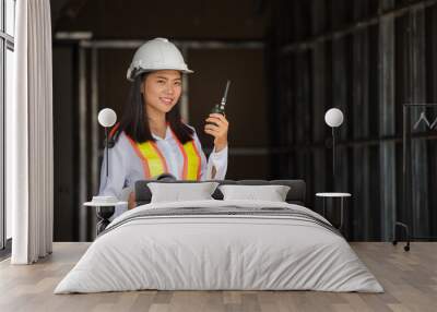 female engineer in white hard hats and blueprints.using walkie-talkie at work. Wall mural