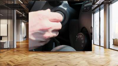 Male hand inserting car key into lock and starting engine close-up Wall mural