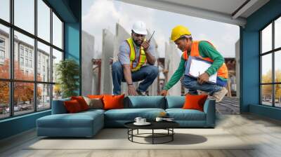 Foreman and laborer checking steel reinforcement cage for making precast concrete wall in construction site. Workers wearing vest and helmet safety working construction site. Wall mural