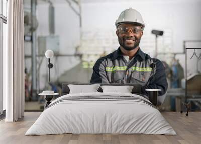 Portrait of African American male engineer in uniform smiling and standing cross arm in industrial factory Wall mural