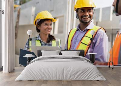 Team of construction engineers wearing vest and helmet safety discussing project at construction site.Group Indian foreman with laptop, paperwork working at factory making precast concrete wall. Wall mural