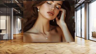 A beautiful woman with long brown hair, wearing pearl earrings and a necklace, looks down with her eyes closed. Wall mural