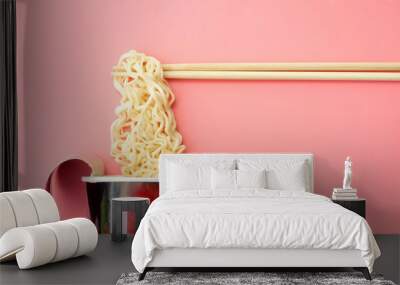 Instant noodles cup and chopsticks on a pink background. Wall mural