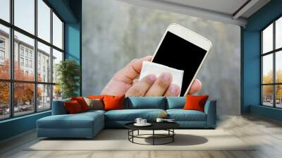 Man cleaning his smartphone with a microfiber cloth. Wall mural