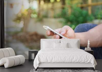 Man using a smartphone in a garden. Wall mural