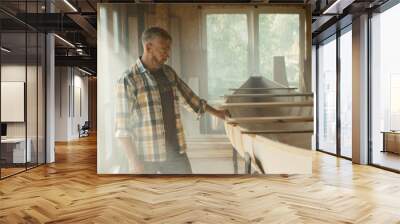 Caucasian male walking near and touching a canoe he made in a workshop. Boat making hobby, small business owner Wall mural