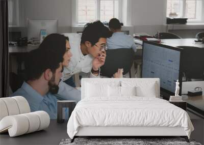 Multi racial team of three office workers communicating together and discussing a project on a computer screen Wall mural