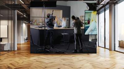 WIDE Behind the scenes of studio set, makeup artist make corrections during shooting television cooking show featuring female chef, professional TV production Wall mural