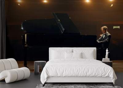 Young 20s aspiring musician playing grand piano on a stage of a huge concert hall Wall mural