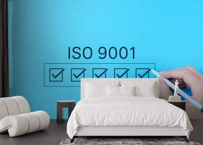 ISO 9001 Quality Assurance Checklist Concept. Hand marking checkboxes for ISO 9001 certification on blue background, symbolizing quality management and assurance standards. Quality control processes, Wall mural