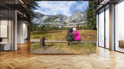 Back view of active family of two, mother and  Daughter enjoying valley and mountain view in yosemite national park, california USA . Active family vacation and Travel concept Wall mural