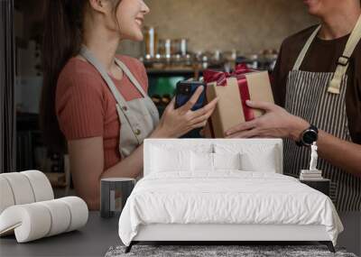 young couple gives a gift box tied with a red ribbon to his girlfriend wearing a apron to surprise his wife while cooking in the kitchen.Gift ideas for birthdays or on Valentine's Day.
​ Wall mural