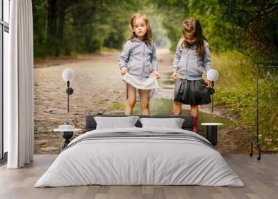 Two little girls walk by the puddle in a summer forest Wall mural