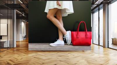 beautiful fashionable big red handbag standing next to leggy woman in white short dress and white sneakers Wall mural