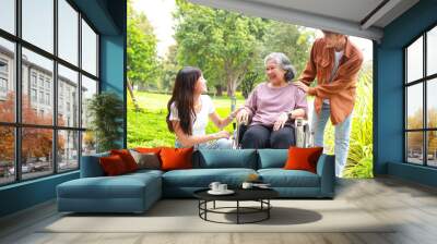 Asian family concept. grandson and granddaughter Take grandma in a wheelchair for a walk in the park. elderly health care Wall mural