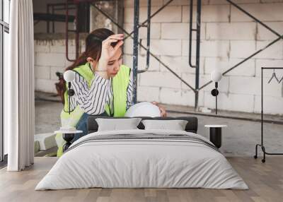 Asian female engineer sitting tired at building construction site. Construction industry concept. worker health care Wall mural