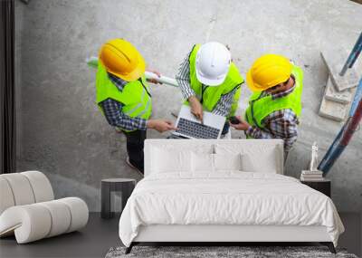 Top view of group of engineers, architects and contractors standing and discussing in building construction site. Industry concept, construction technology Wall mural