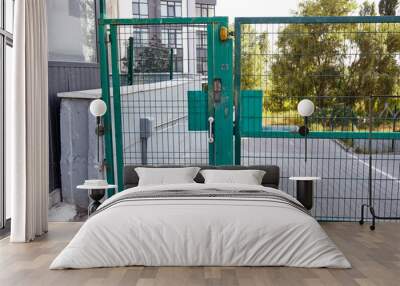 Front door of the courtyard. Metal Wire Fence.Green metal driveway entrance gates. Remote control to open swing gate door by motor automation is home security system Wall mural