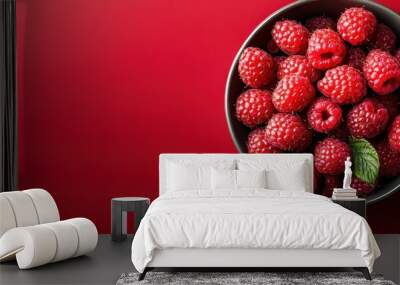 Fresh and juicy raspberries in a black bowl on a vibrant red background, perfect for healthy eating and cooking, background with copy space Wall mural