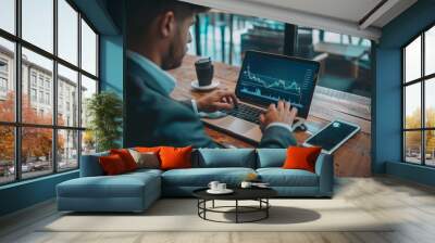 A businessman analyzing market trends on a laptop, staying informed and proactive in business strategy Wall mural