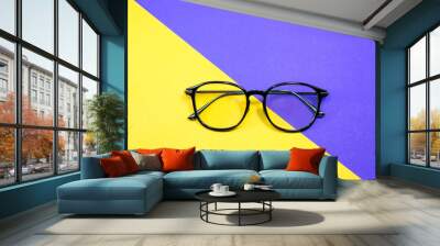 Modern frame glasses on yellow and violet background.  Beauty and fashion concept. Wall mural