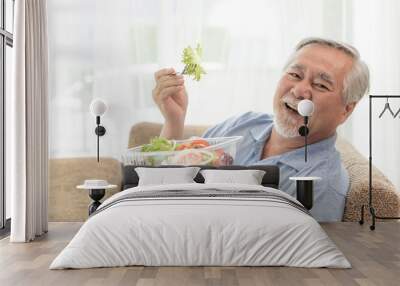 Lifestyle senior man feel happy enjoy eating diet food fresh salad on sofa Wall mural